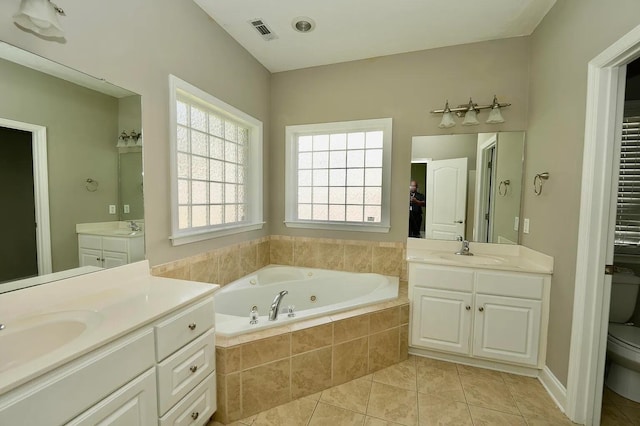 bathroom featuring tile patterned flooring, vanity, toilet, and tiled tub