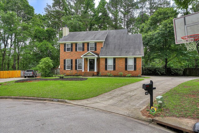 864 Chase Rd, Evans, GA 30809 - colonial house featuring brick siding, concrete driveway, a chimney, view of scattered trees, and roof with shingles
