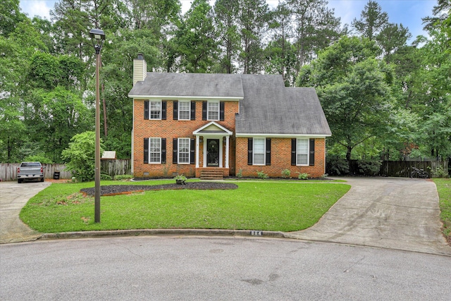 864 Chase Rd, Evans, GA 30809 - colonial house featuring concrete driveway, a chimney, brick siding, and view of wooded area