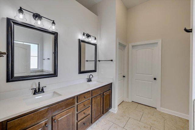 full bath with double vanity, a sink, and baseboards