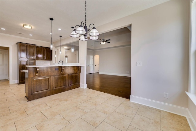 kitchen with arched walkways, light tile patterned floors, light countertops, ceiling fan, and a peninsula