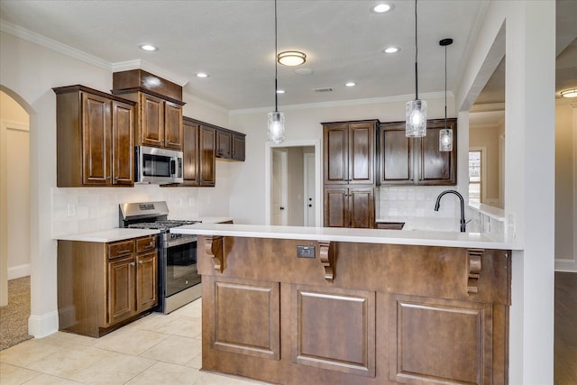 kitchen featuring arched walkways, a peninsula, appliances with stainless steel finishes, and crown molding