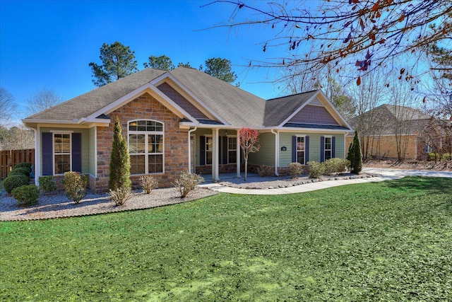 view of front of home with stone siding, fence, and a front yard