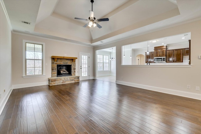 unfurnished living room featuring visible vents, a raised ceiling, ornamental molding, dark wood-style flooring, and a fireplace