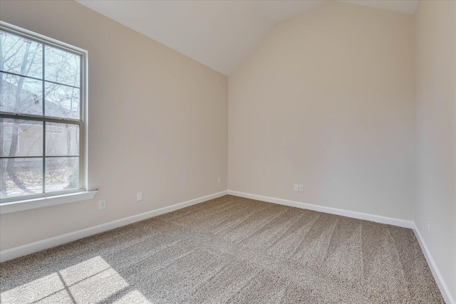 spare room featuring vaulted ceiling, carpet floors, and baseboards