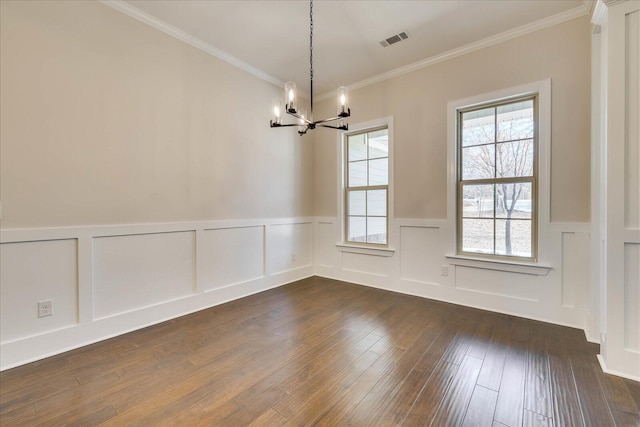 empty room featuring visible vents, dark wood finished floors, a wainscoted wall, ornamental molding, and an inviting chandelier