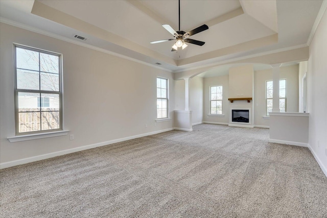 unfurnished living room featuring visible vents, baseboards, carpet, a tray ceiling, and crown molding