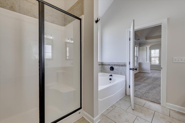 bathroom with a shower stall, a bath, and baseboards