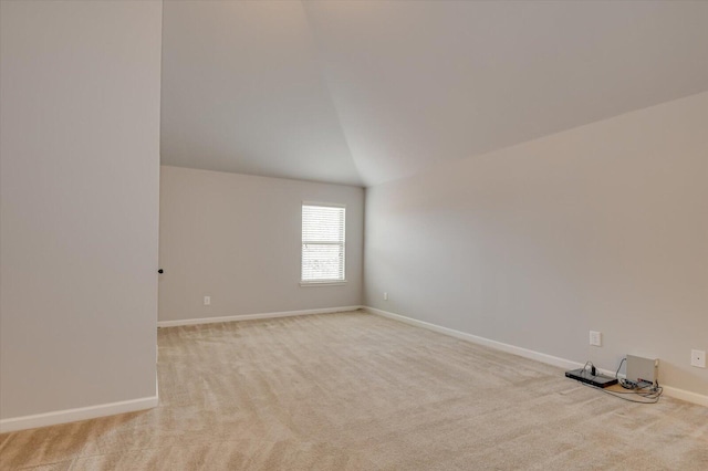 carpeted empty room featuring vaulted ceiling