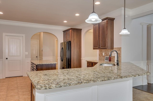 kitchen with pendant lighting, sink, a kitchen island, and black fridge