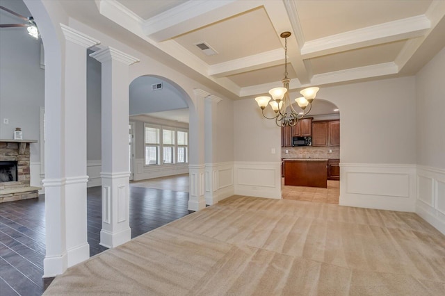 interior space with a fireplace, beamed ceiling, ornate columns, and ceiling fan with notable chandelier