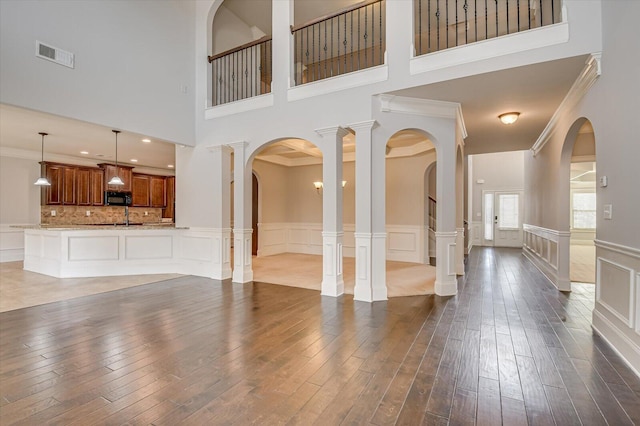 unfurnished living room featuring ornamental molding, dark wood-type flooring, and ornate columns