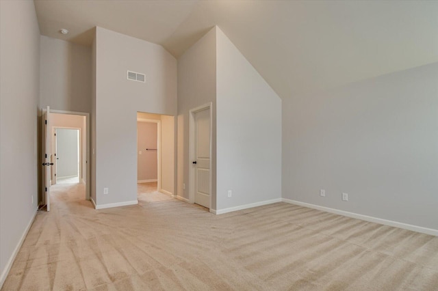 unfurnished bedroom with light carpet, high vaulted ceiling, and a walk in closet