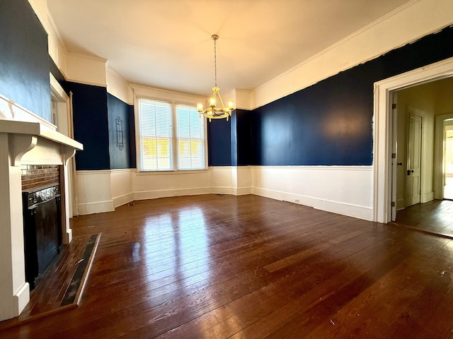 unfurnished dining area with ornamental molding, dark hardwood / wood-style floors, a brick fireplace, and a notable chandelier