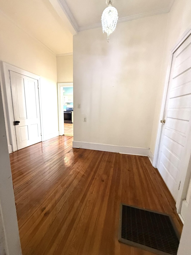 unfurnished dining area featuring an inviting chandelier, ornamental molding, and hardwood / wood-style floors