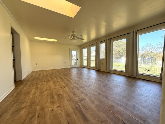 spare room with dark hardwood / wood-style floors, ceiling fan, and a skylight