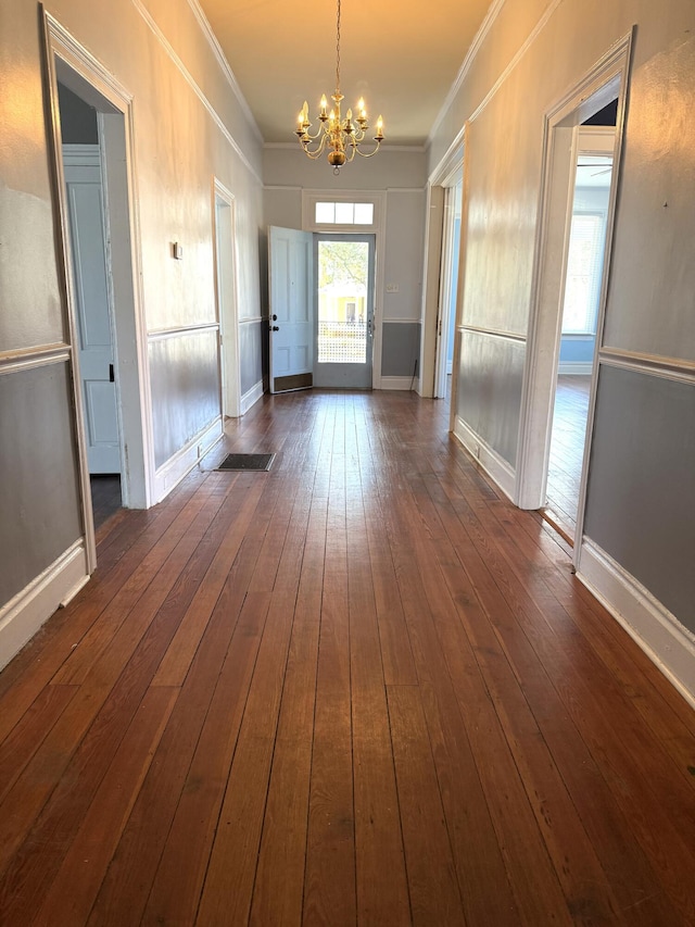 interior space with ornamental molding, an inviting chandelier, and dark hardwood / wood-style flooring