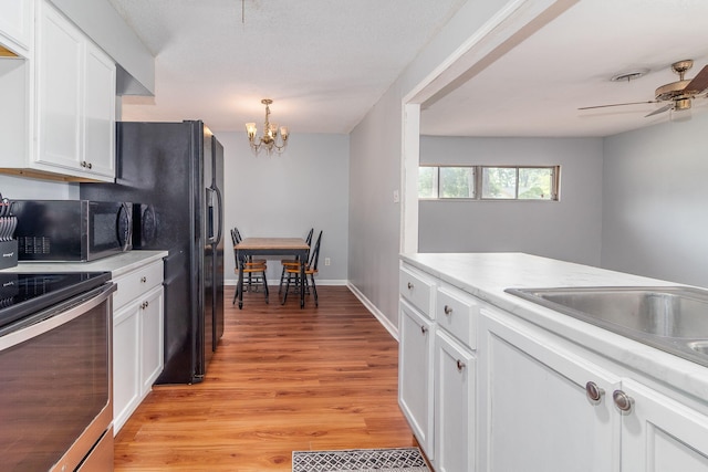2383 Wheeless Rd, Augusta, GA 30906 - kitchen with stove, black microwave, white cabinets, a chandelier, and light countertops
