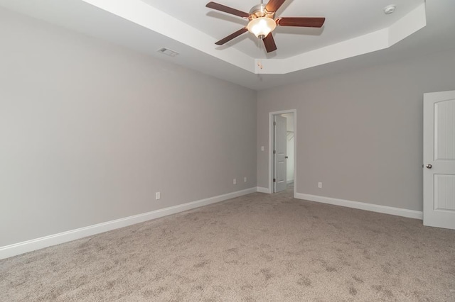 spare room featuring a raised ceiling, a ceiling fan, carpet flooring, a smoke detector, and baseboards