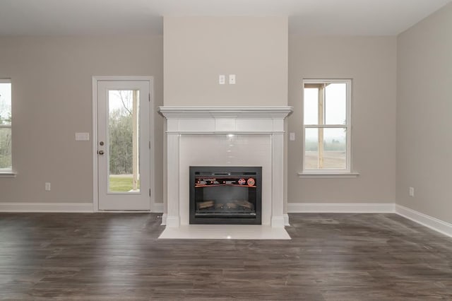 unfurnished living room with dark wood-style flooring, a fireplace with flush hearth, and baseboards