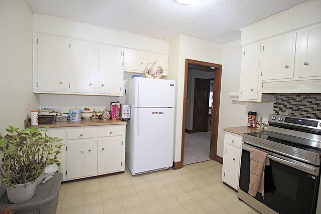 kitchen with a textured ceiling, white refrigerator, white cabinetry, and stainless steel range with electric cooktop