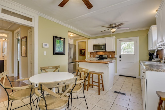 1743 King Woods Dr, Augusta, GA 30904 - kitchen with stainless steel appliances, a sink, ceiling fan, white cabinetry, and crown molding