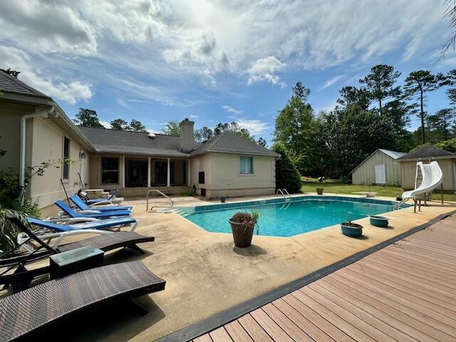 3129 Goolsby Rd, Blythe, GA 30805 - outdoor pool featuring a water slide, a shed, a wooden deck, a patio area, and a diving board