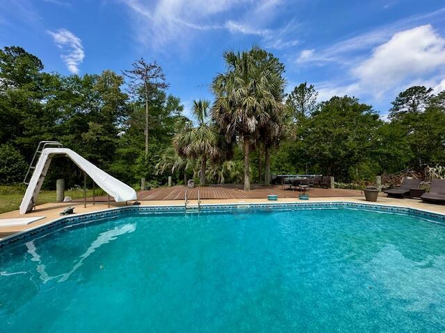 3129 Goolsby Rd, Blythe, GA 30805 - outdoor pool with a water slide, view of wooded area, and a diving board