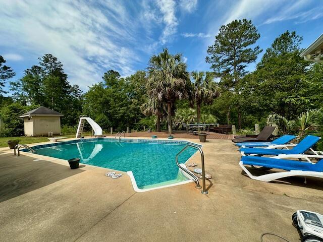 3129 Goolsby Rd, Blythe, GA 30805 - swimming pool featuring a patio, view of wooded area, a water slide, and a diving board