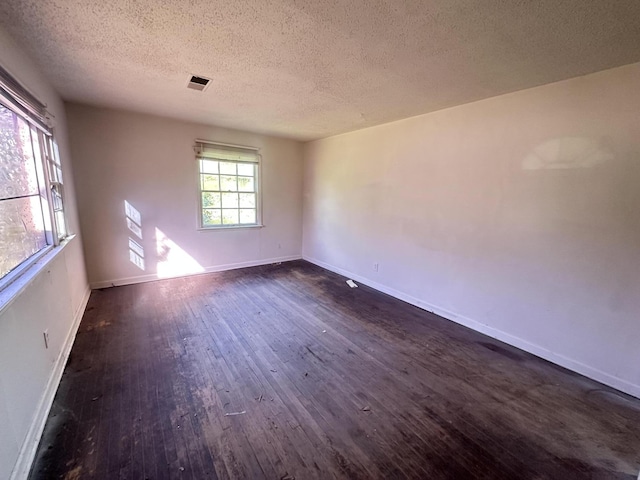 unfurnished room with a textured ceiling and dark hardwood / wood-style floors