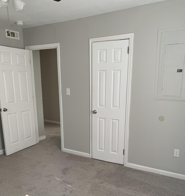 unfurnished bedroom with light colored carpet and electric panel