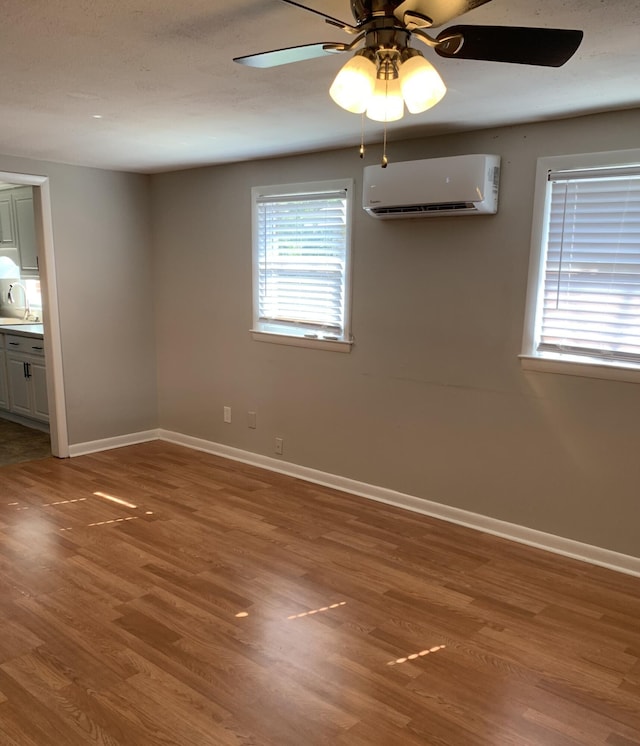 spare room featuring hardwood / wood-style flooring, an AC wall unit, a healthy amount of sunlight, and sink