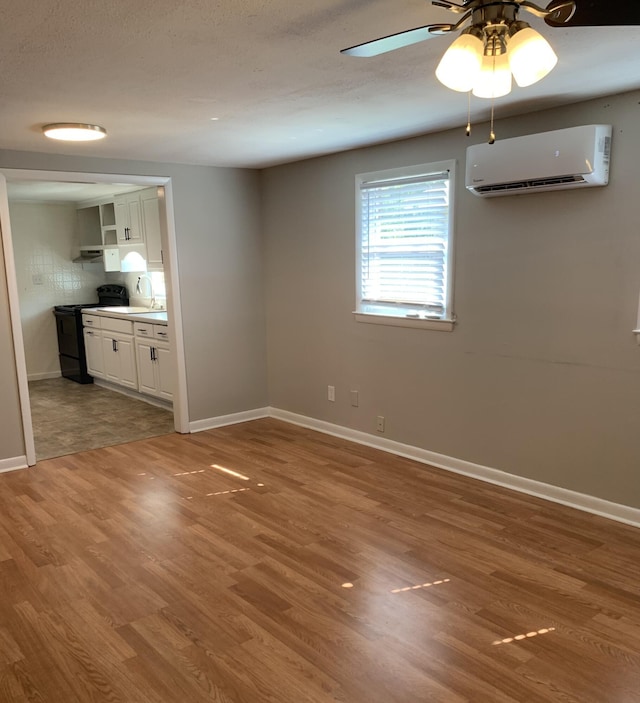 interior space featuring ceiling fan, wood-type flooring, and an AC wall unit