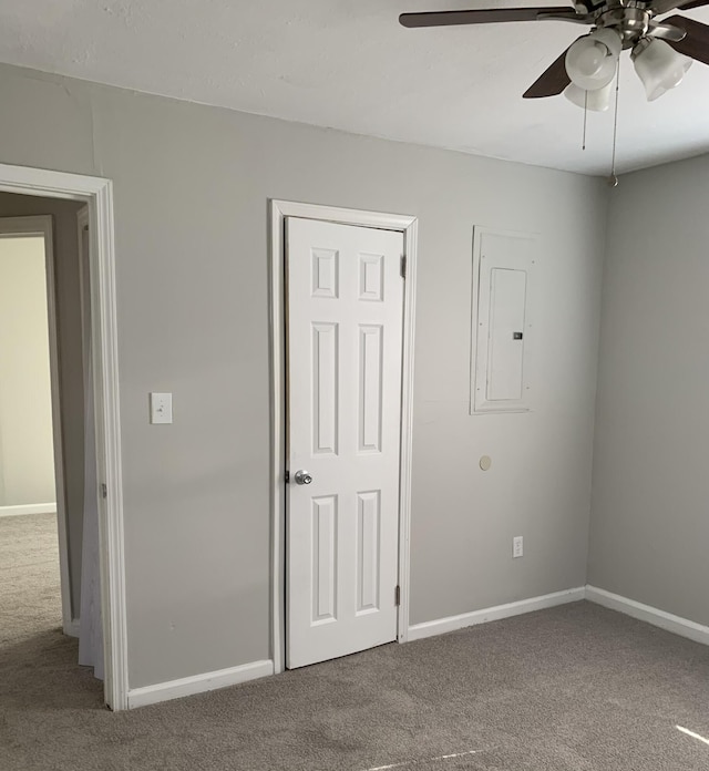 empty room with carpet floors, electric panel, and ceiling fan