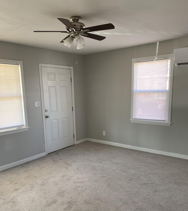 spare room with a wall mounted air conditioner, light colored carpet, and ceiling fan