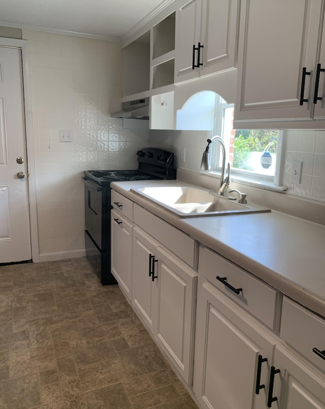 kitchen with tasteful backsplash, sink, white cabinets, and black / electric stove