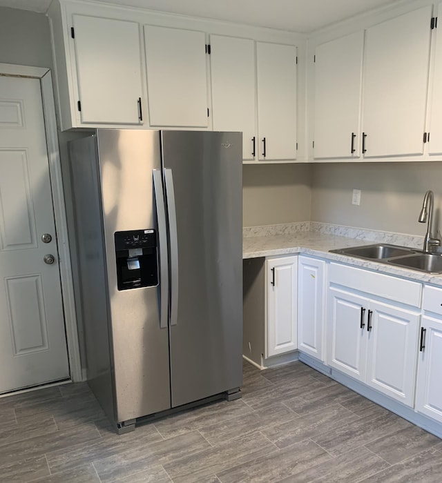 kitchen with stainless steel fridge, sink, light hardwood / wood-style flooring, and white cabinets