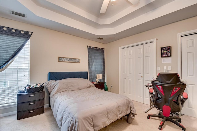 carpeted bedroom with ceiling fan and a tray ceiling