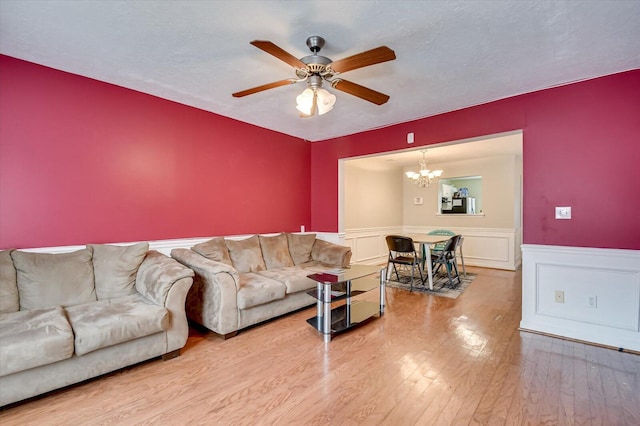 living room featuring hardwood / wood-style floors, ceiling fan with notable chandelier, and a textured ceiling