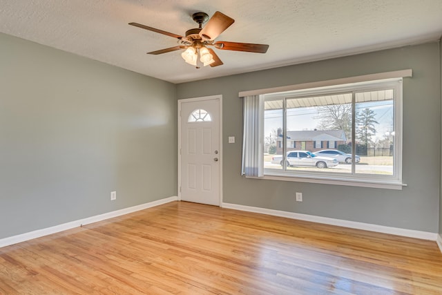 entryway featuring light wood-type flooring, ceiling fan, baseboards, and a textured ceiling