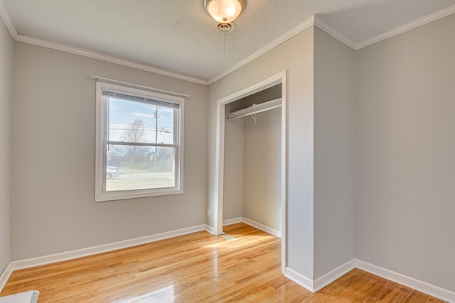 unfurnished bedroom featuring light wood-style floors, crown molding, and baseboards