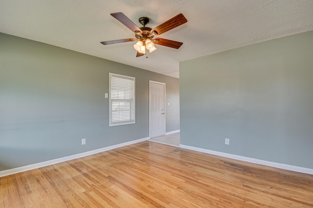 unfurnished room featuring a ceiling fan, light wood-type flooring, a textured ceiling, and baseboards