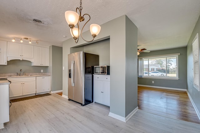 kitchen featuring stainless steel appliances, light wood finished floors, light countertops, and white cabinetry