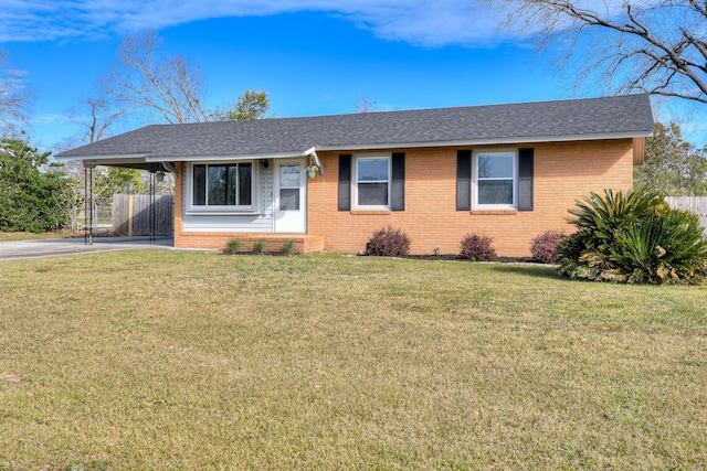 view of front facade with a carport, a front yard, brick siding, and fence