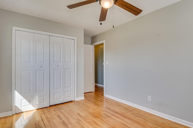 unfurnished bedroom with a ceiling fan, a closet, light wood-style flooring, and baseboards