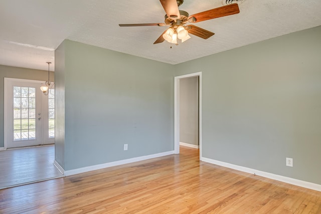 empty room featuring a textured ceiling, light wood finished floors, a ceiling fan, and baseboards