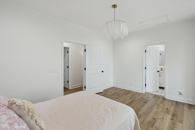 1513 Paris Ave, Swainsboro, GA 30401 - bedroom with wood finished floors, attic access, ensuite bath, and a chandelier