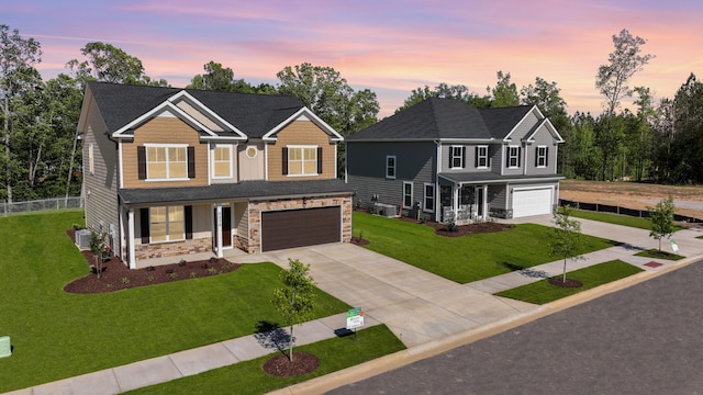 view of front facade with central AC unit, concrete driveway, stone siding, an attached garage, and a front lawn