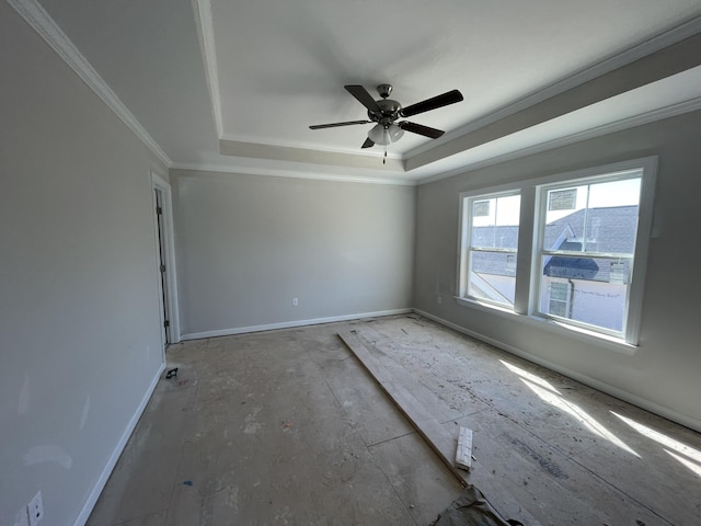 spare room with a raised ceiling, crown molding, baseboards, and ceiling fan