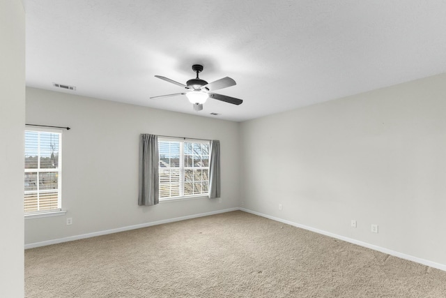 carpeted spare room with ceiling fan and plenty of natural light